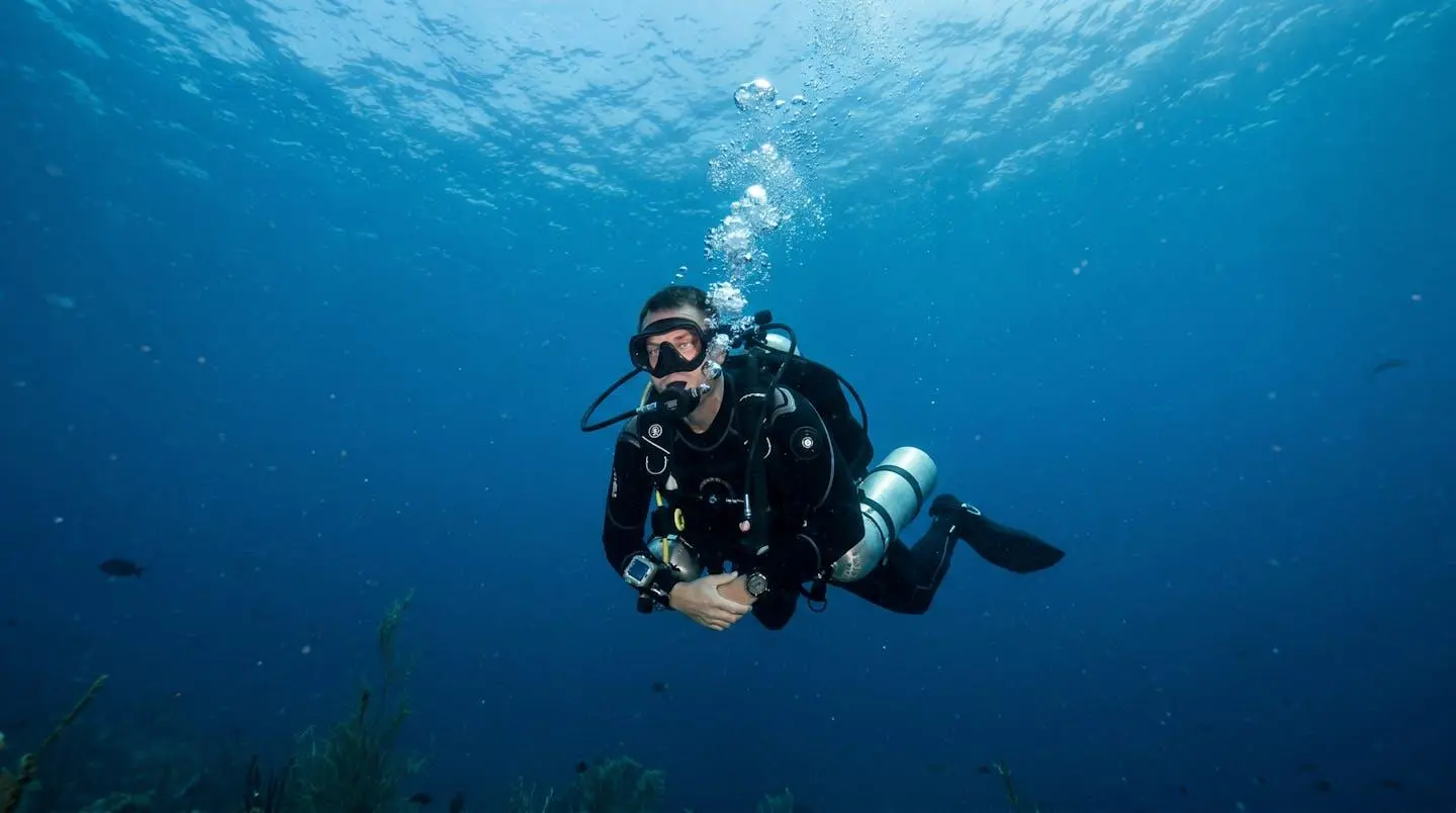 Plongeur en équipement complet effectuant une remontée de sécurité contrôlée sous l'eau avec bulles d'air visibles